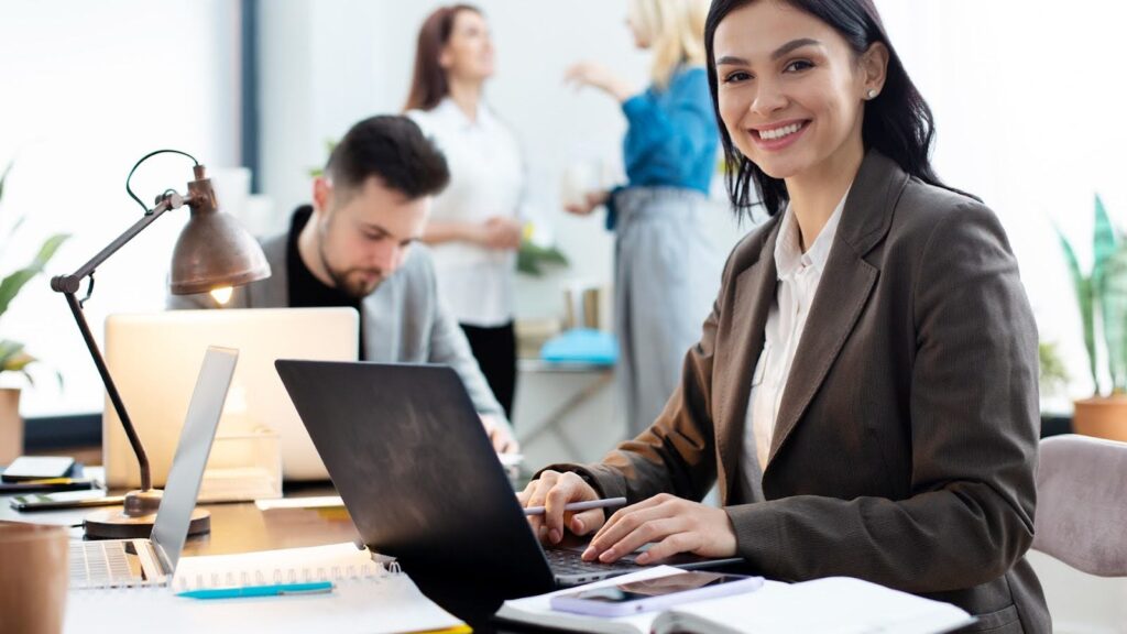 Girl looking at the camera with her laptop in front of her